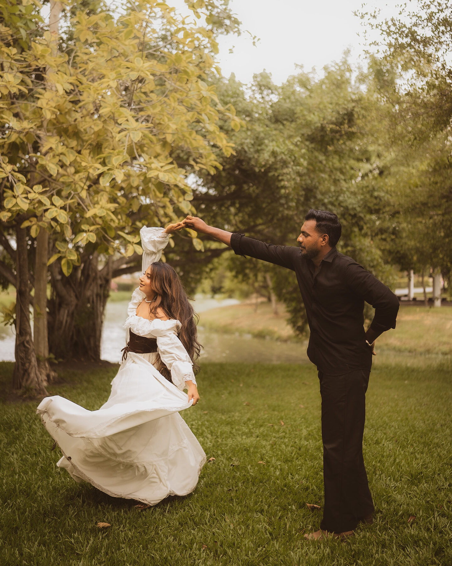 Bride and groom dancing beneath golden trees at sunset
